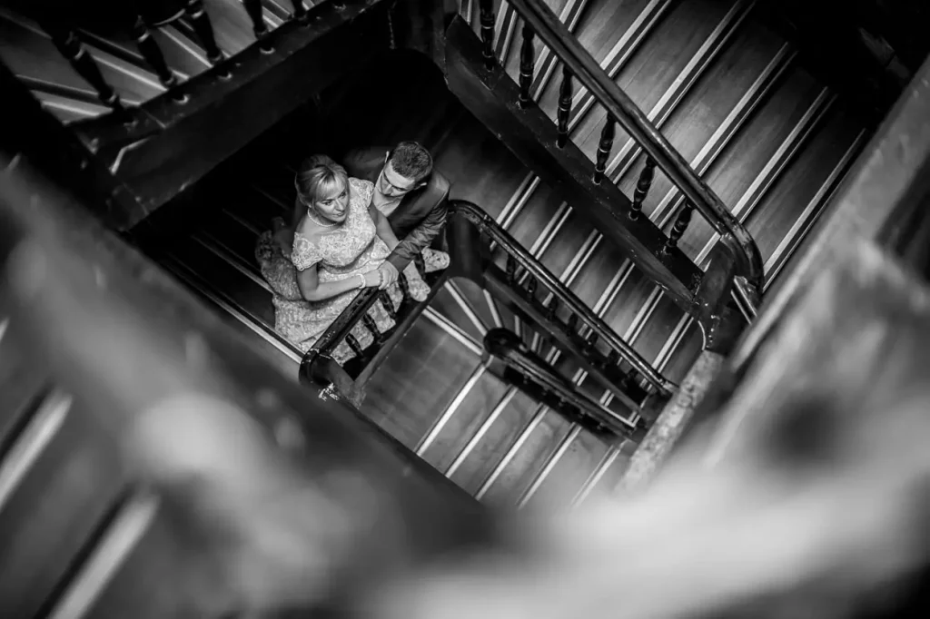 Чорно-біла весільна зйомка зверху, молодята на старовинних дерев'яних сходах у Львові, професійне портфоліо фотографа RoStudio.