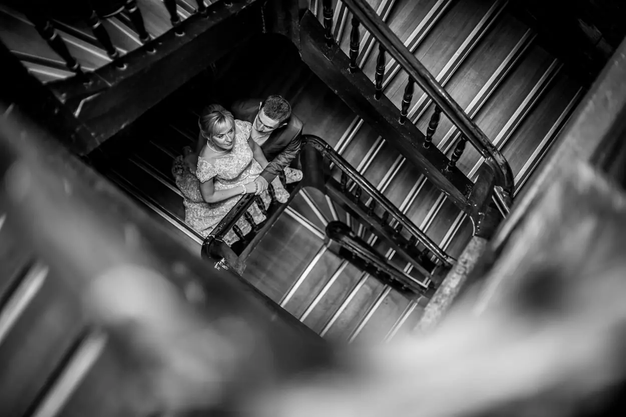 Чорно-біла весільна зйомка зверху, молодята на старовинних дерев'яних сходах у Львові, професійне портфоліо фотографа RoStudio.